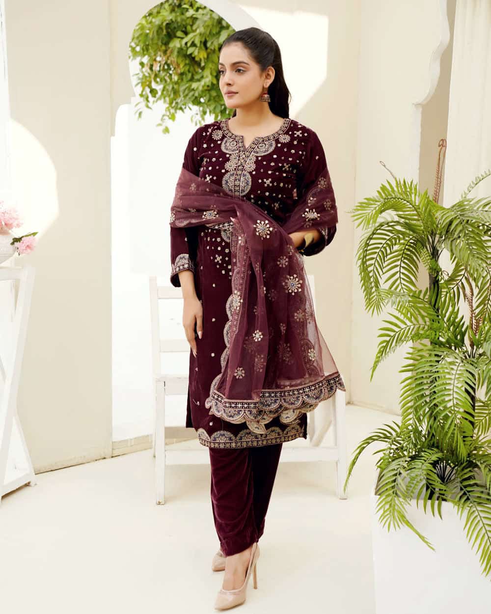 An embroidered salwar suit in deep maroon with a matching dupatta