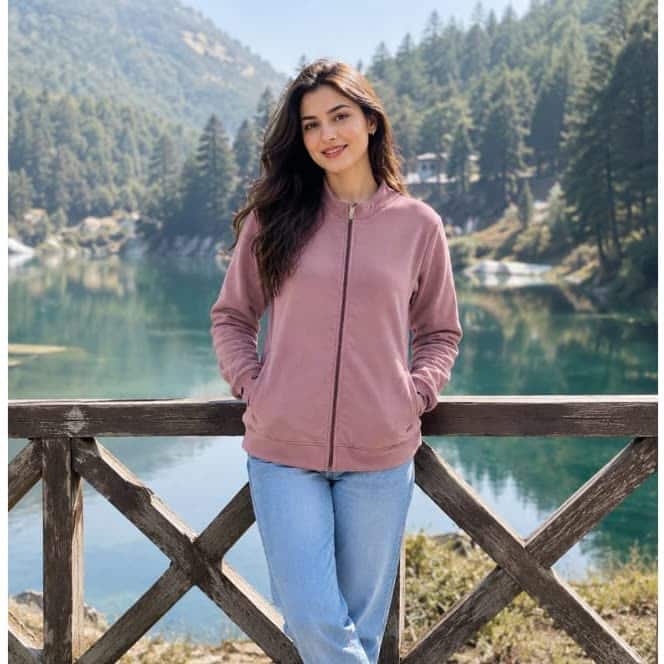 A women's dusty pink fleece jacket worn open over jeans, photographed outdoors