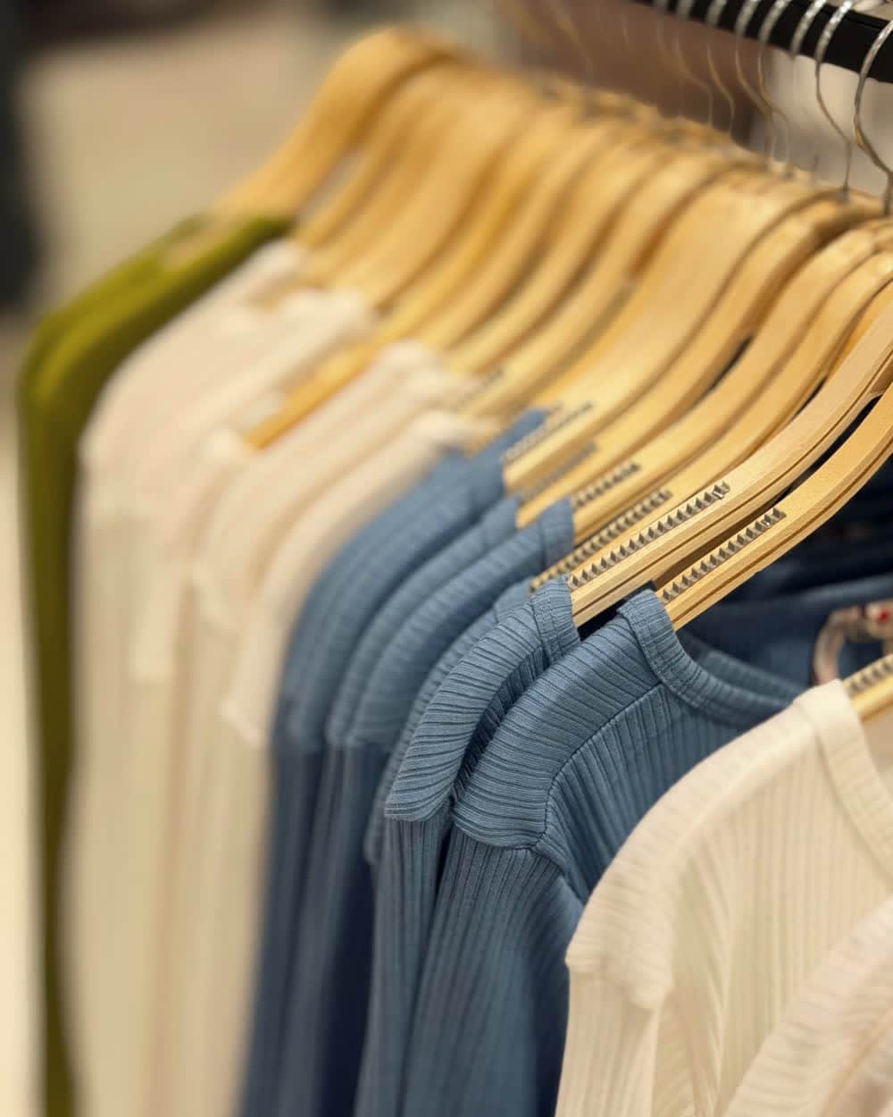 Shirts on wooden hangers along a rail, arranged as a run of colour