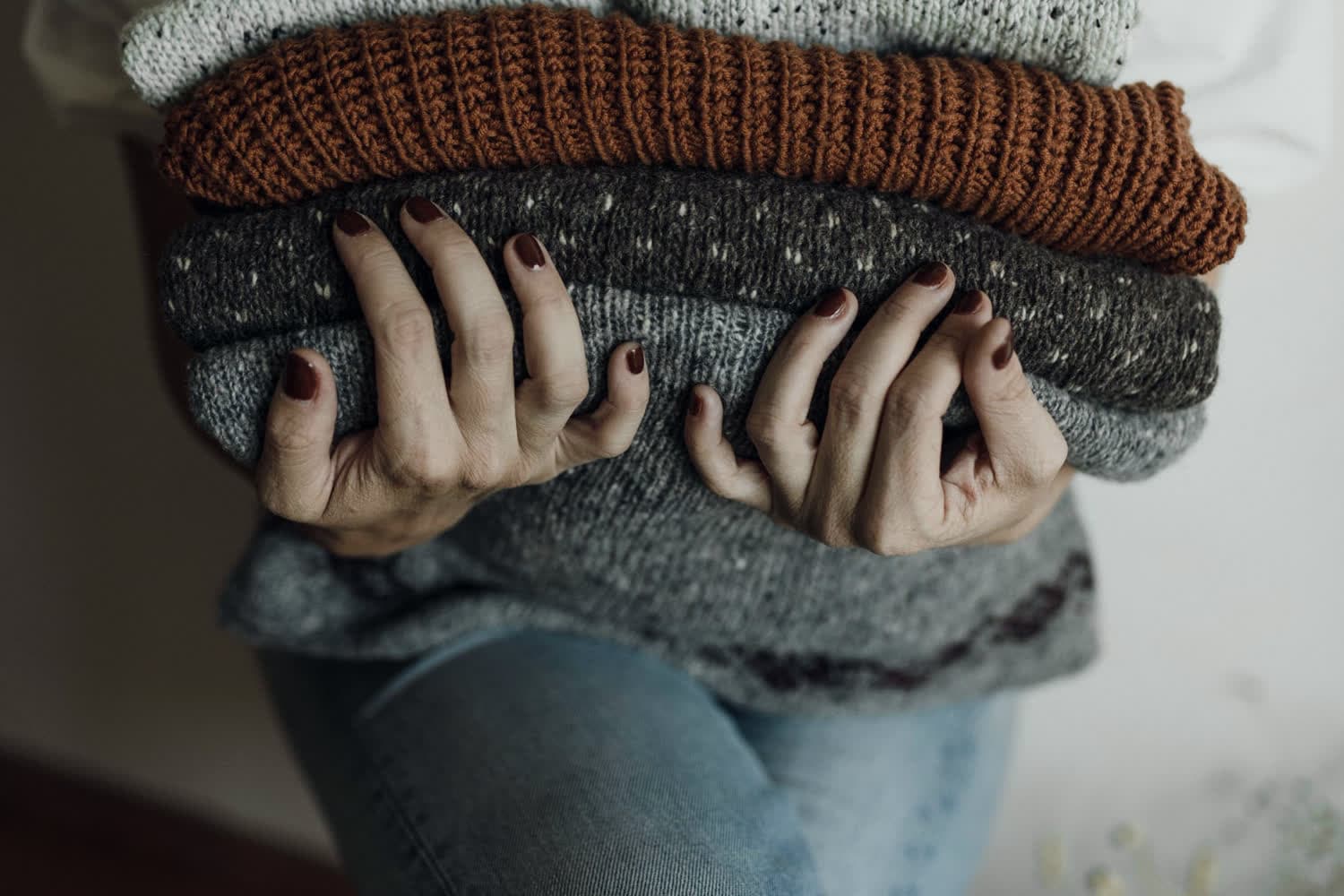 Hands holding a folded stack of knitted cloth, checking the weight of it