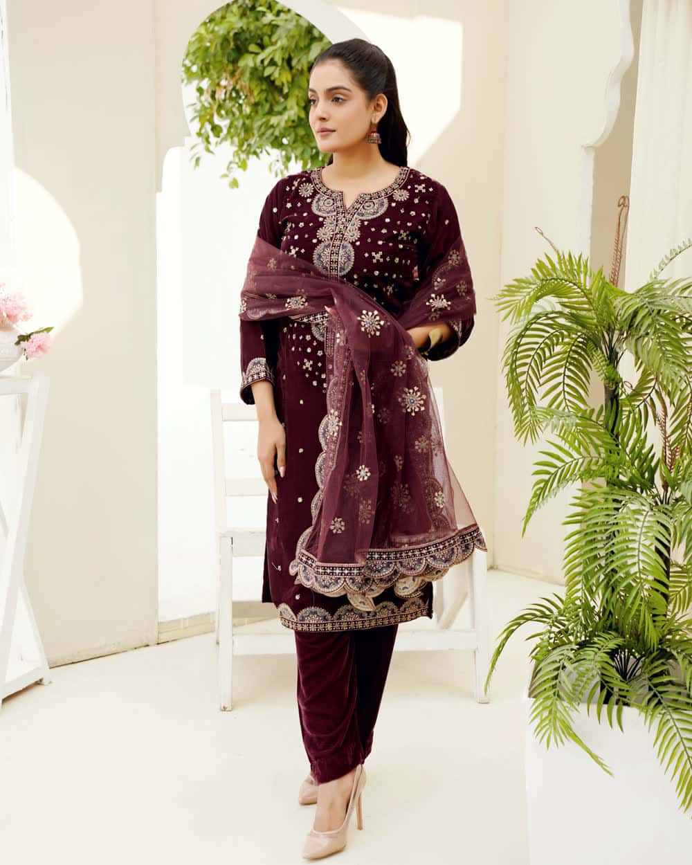 An embroidered salwar suit in deep maroon with a matching dupatta
