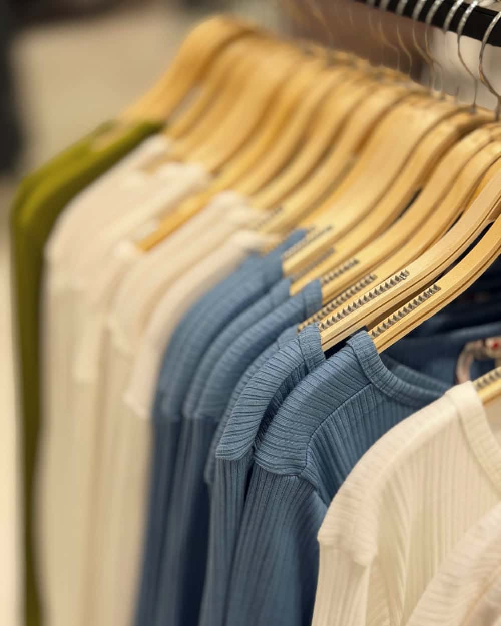 Shirts on wooden hangers along a rail, arranged as a run of colour